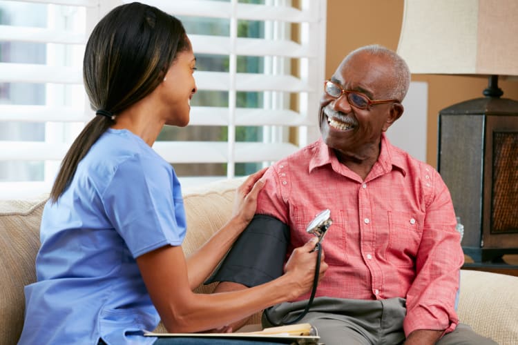 Nurse visiting senior male patient at home taking blood pressure
